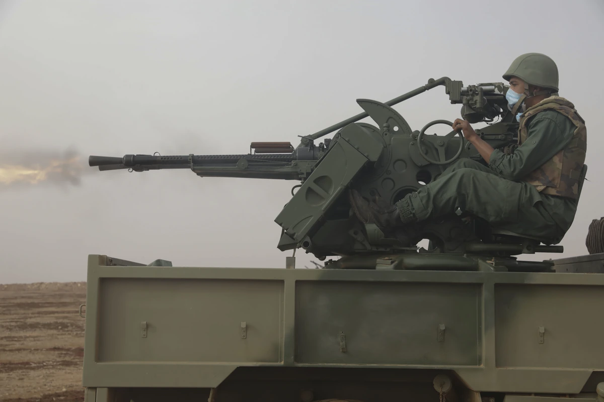 Soldiers firing a vehicle-mounted DShK heavy machine gun during a live-fire exercise