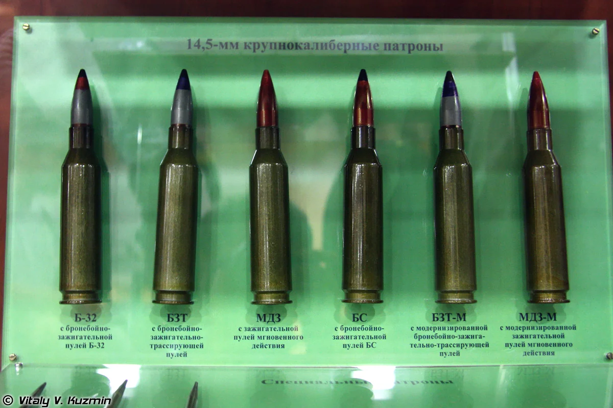 Four 14.5×114mm cartridges with different coloured bullet tips displayed upright in a case, each labelled
