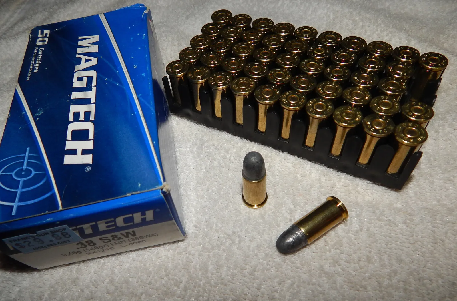 A box of .38 Smith & Wesson cartridges with two loose rounds standing beside it, showing rounded lead bullets in brass cases