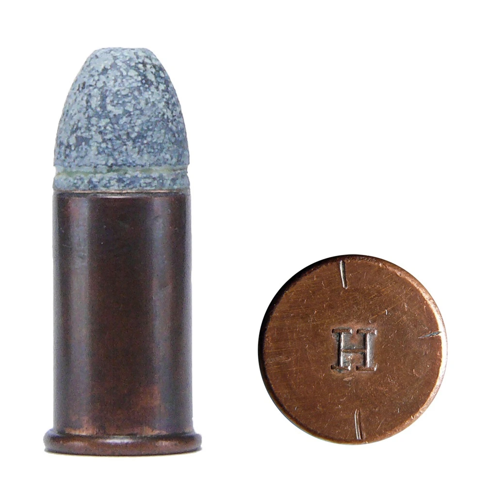 A copper rimfire cartridge with a rounded lead bullet, beside its own headstamped base