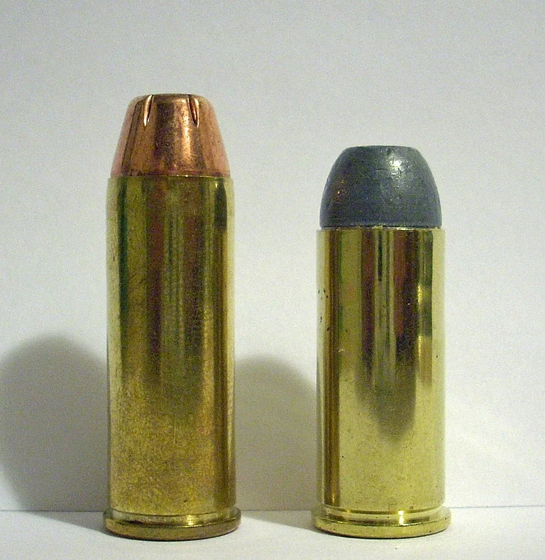 Two straight-walled brass revolver cartridges standing side by side on a white ground: on the left a longer one with a jacketed hollow-point bullet, on the right a slightly shorter one with a grey lead bullet.
