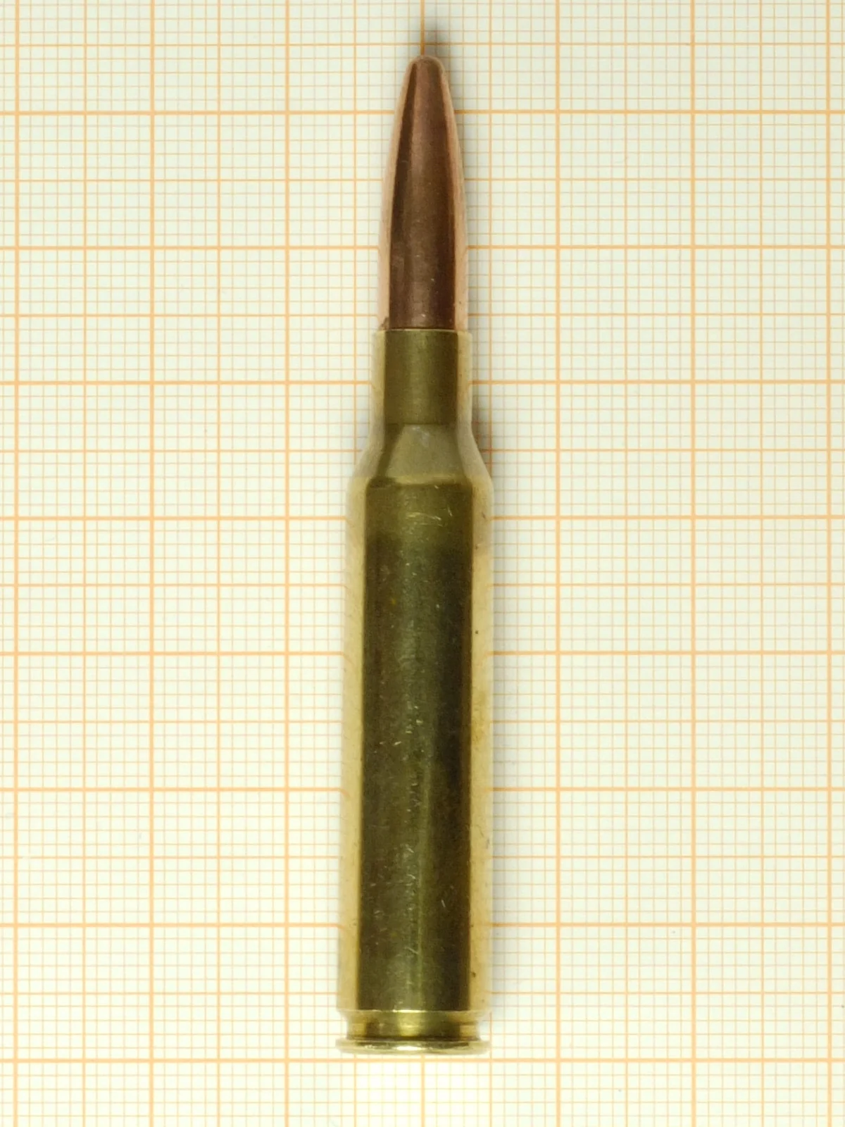 A single brass bottleneck rifle cartridge with a round-nosed bullet, standing upright on a grid background