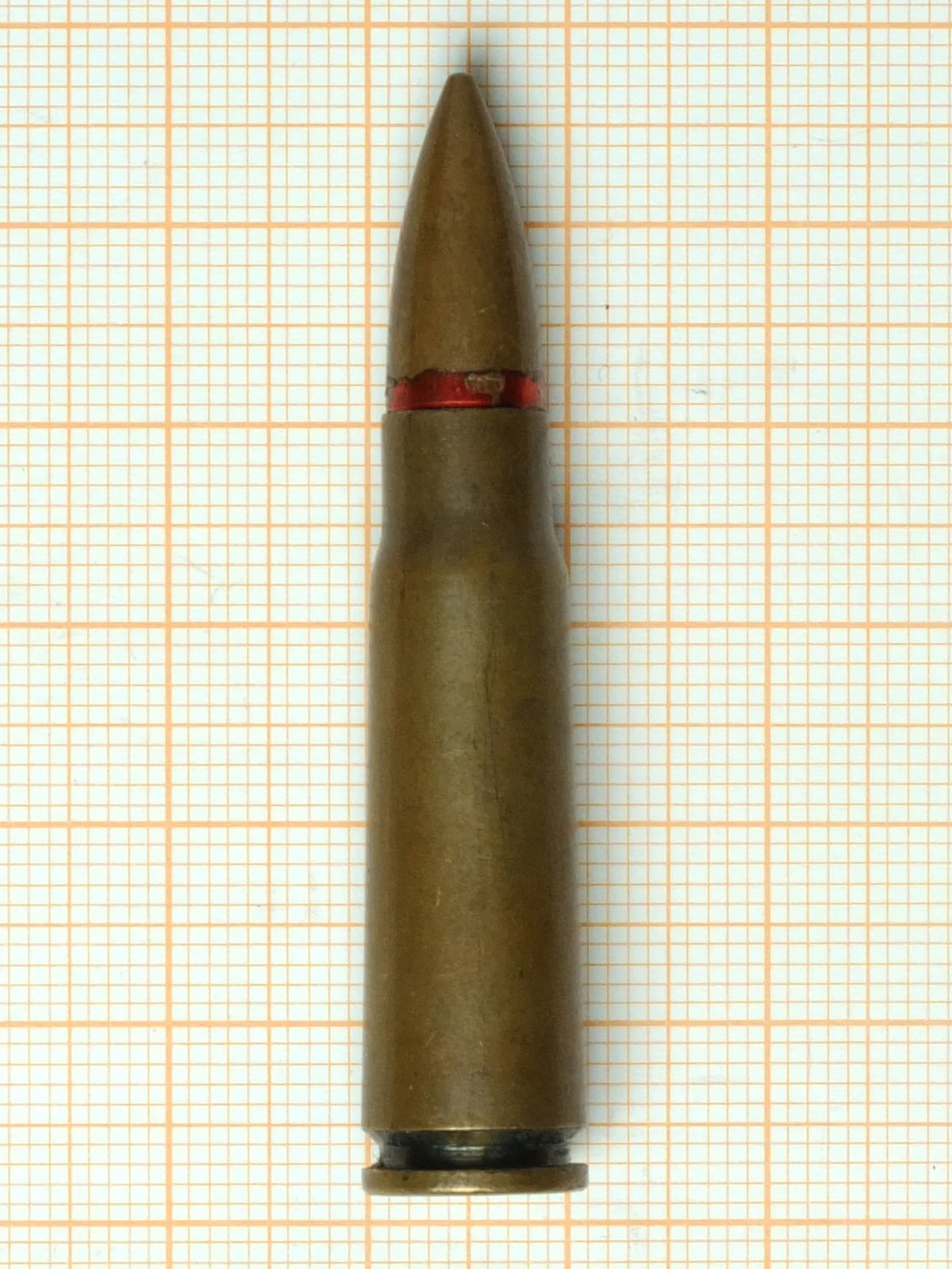 A 7.62x39mm cartridge with a lacquered steel case photographed upright