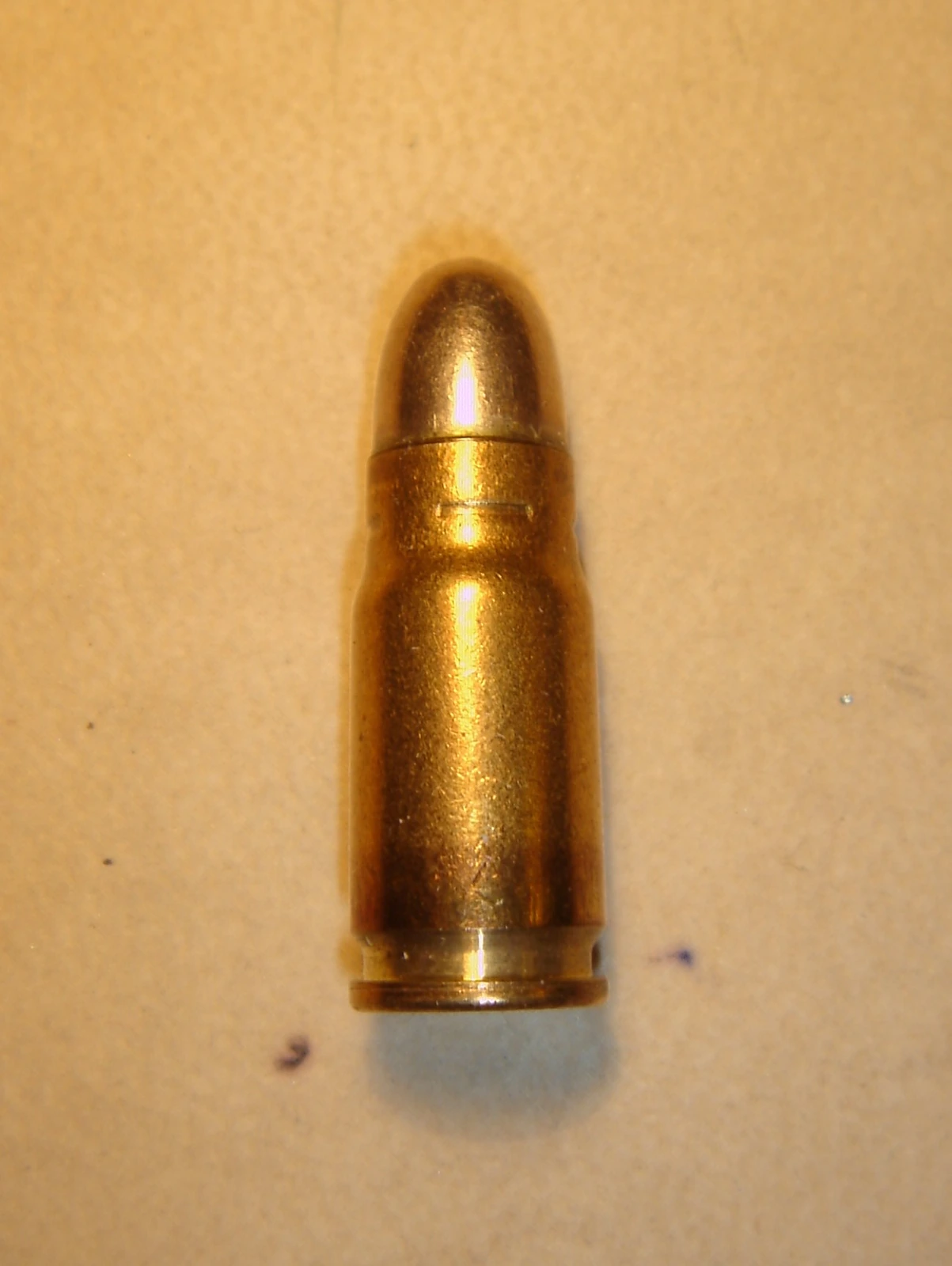 A single rimless bottleneck pistol cartridge with a rounded full-metal-jacket bullet, on a plain background.