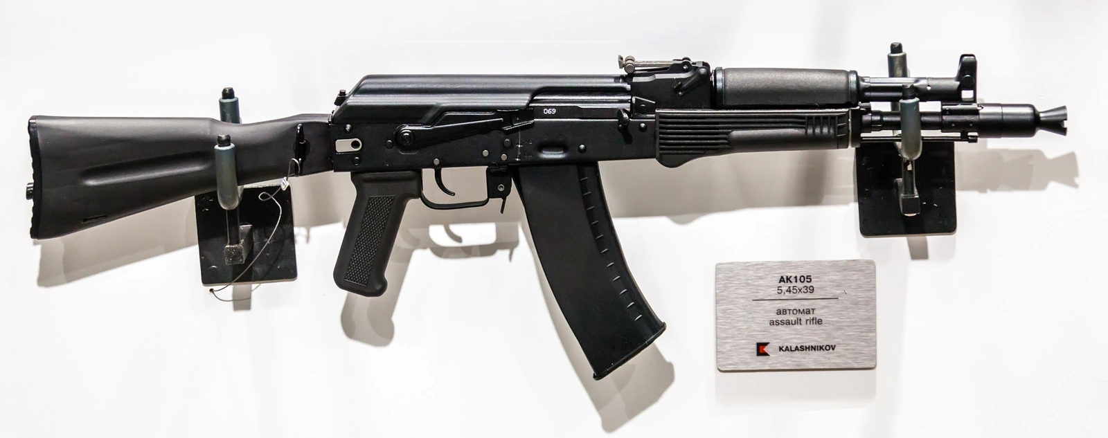 A black AK-105 carbine with a side-folding stock and a short curved magazine, photographed against a plain background