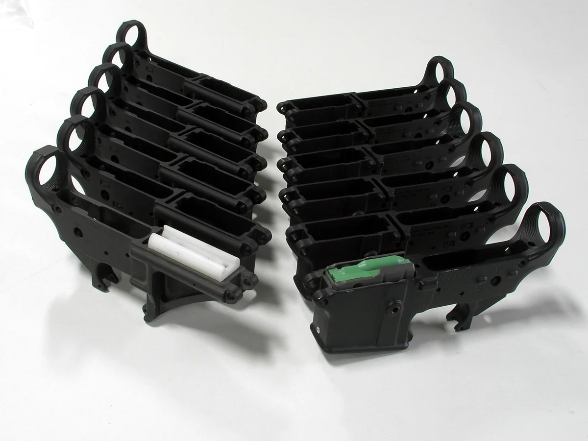 Several stripped AR-15 lower receivers laid out on a bench