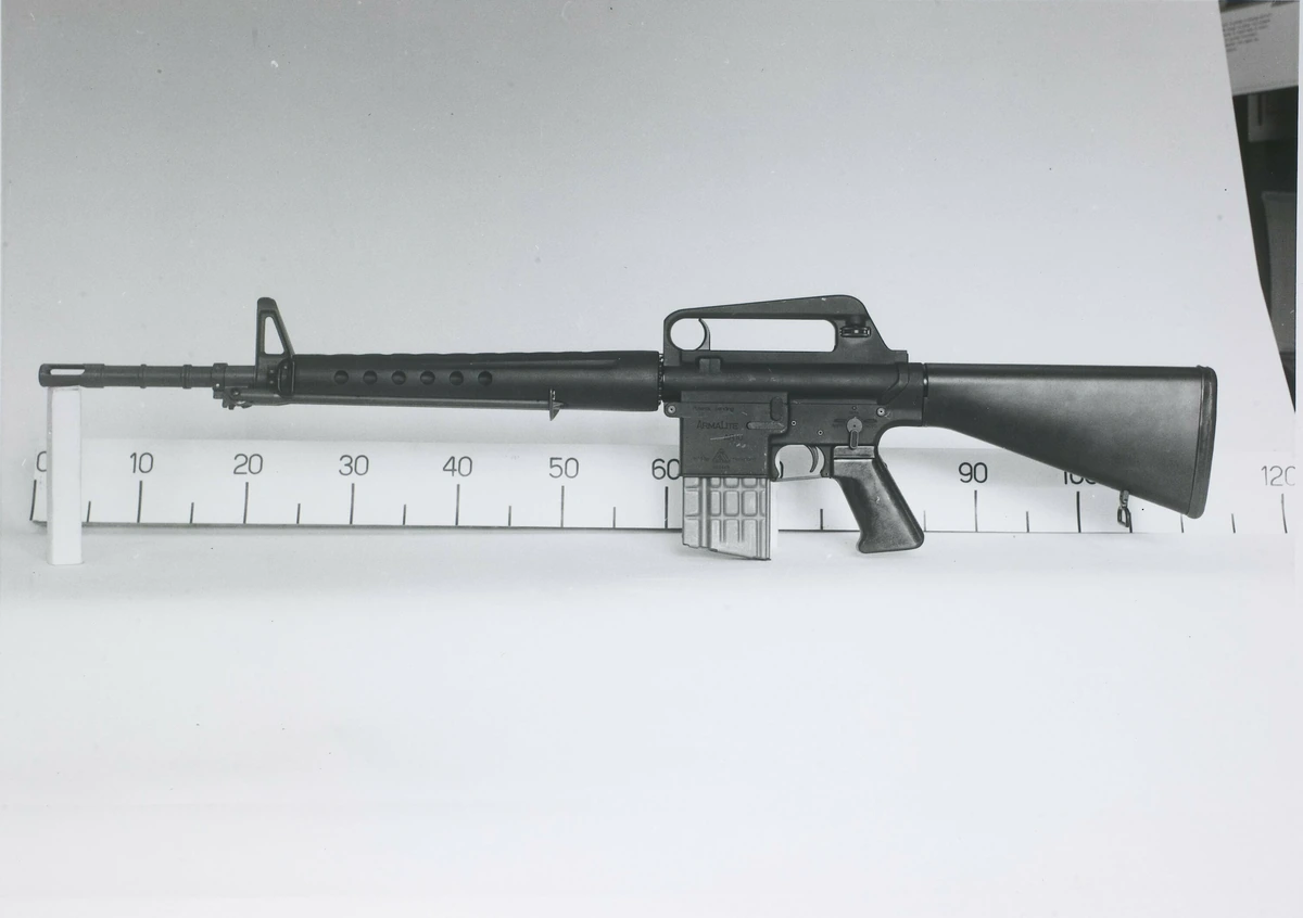 A black-and-white archival photograph of an AR-10 rifle laid along a measuring scale marked in centimetres, its curved magazine and ARMALITE marking visible on the lower receiver.