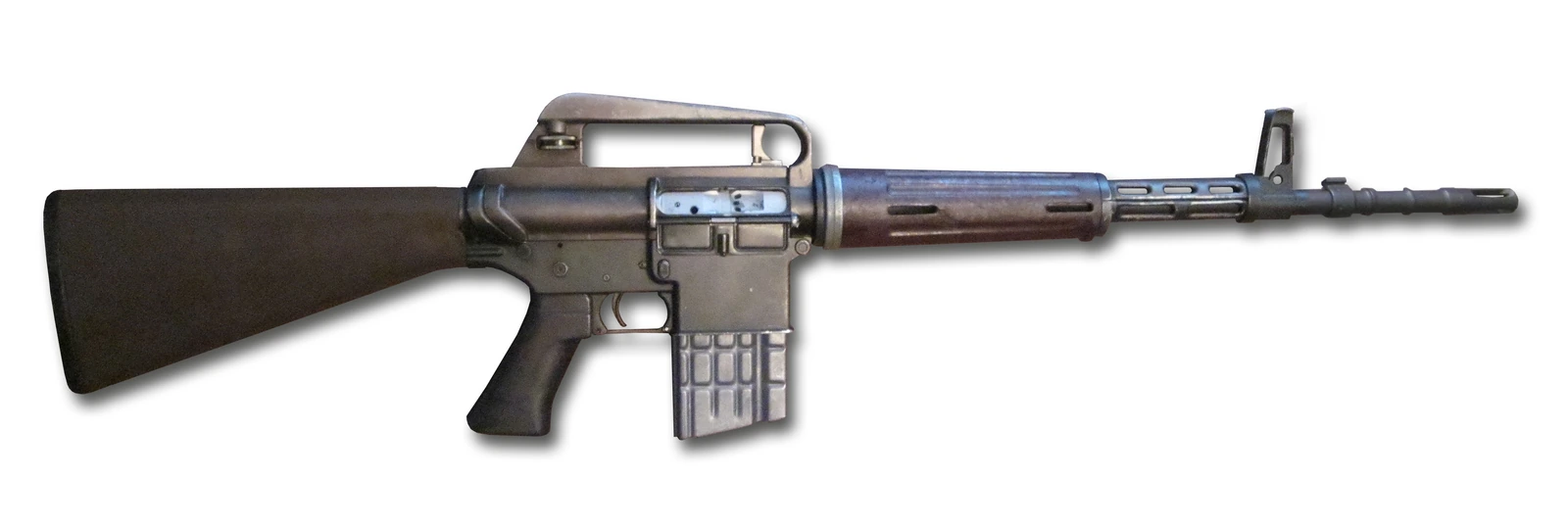 A rifle with a straight-line stock, a carrying handle over the receiver, a fluted handguard, a curved box magazine and a distinctive triangular flash suppressor at the muzzle.