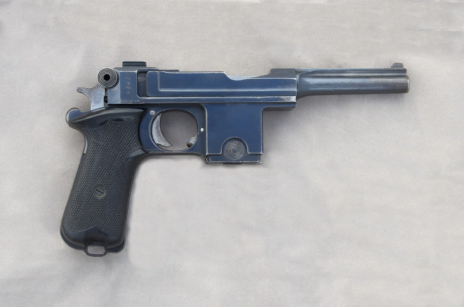 A blued steel semi-automatic pistol with a long slide-lock mechanism and a wooden grip, photographed from the right side against a plain grey background