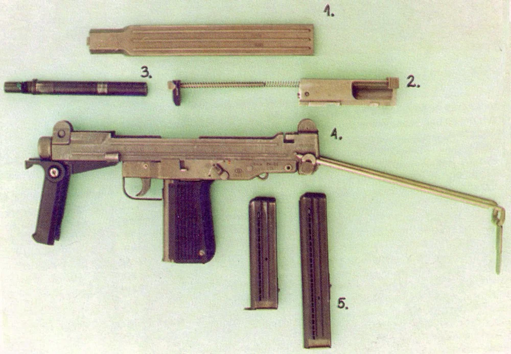 A labeled diagram showing a PM-84 submachine gun field-stripped into its receiver, bolt, barrel and two magazines