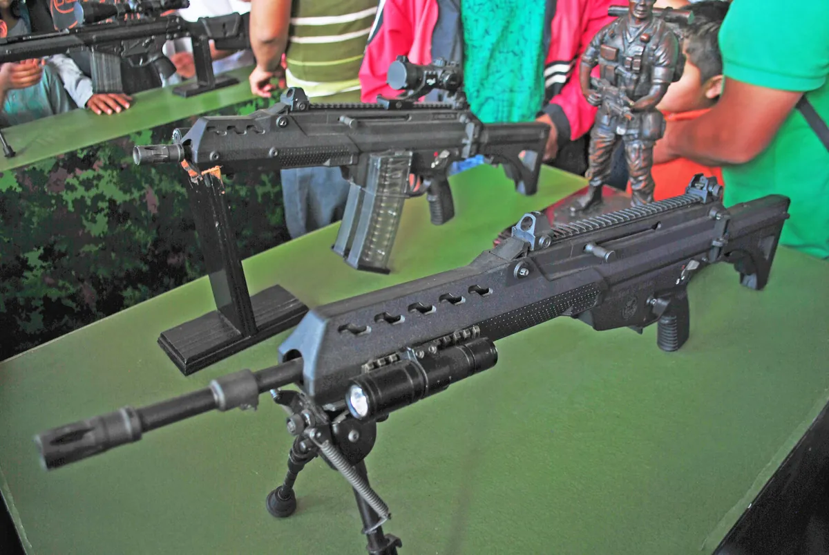 Two second-generation FX-05 rifles, an assault rifle and a carbine, on stands at a public exhibition