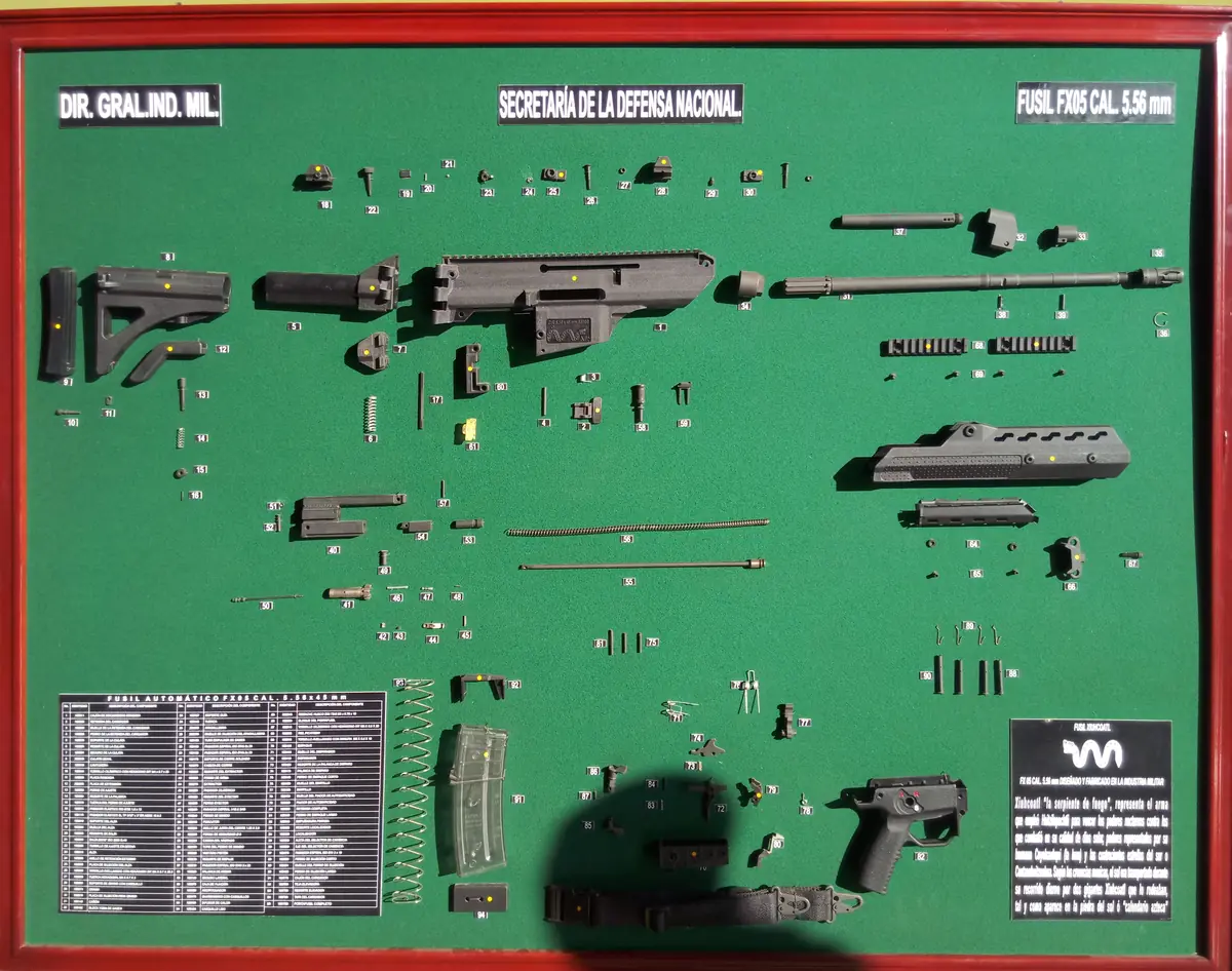 An FX-05 rifle's components laid out separately on a green display board