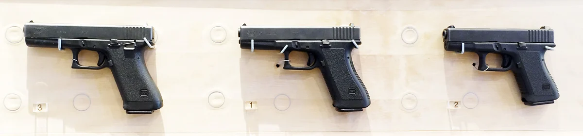 A row of Glock pistols displayed in a museum case