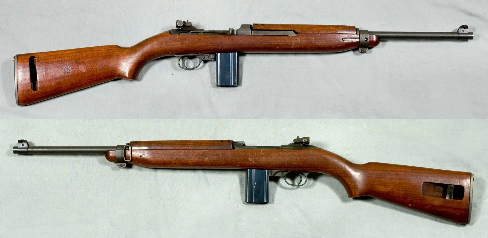 Two views of an M1 carbine on a pale cloth, left and right sides, with a slim walnut stock, a short barrel and a straight box magazine ahead of the trigger guard