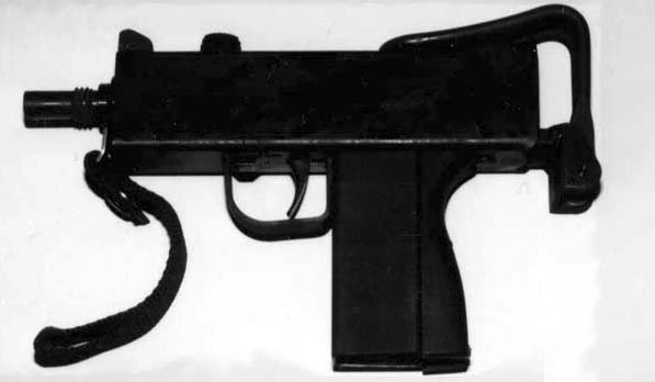 A black MAC-11-pattern submachine gun with a folding wire shoulder stock extended to the rear and a fabric sling looped beneath the receiver.