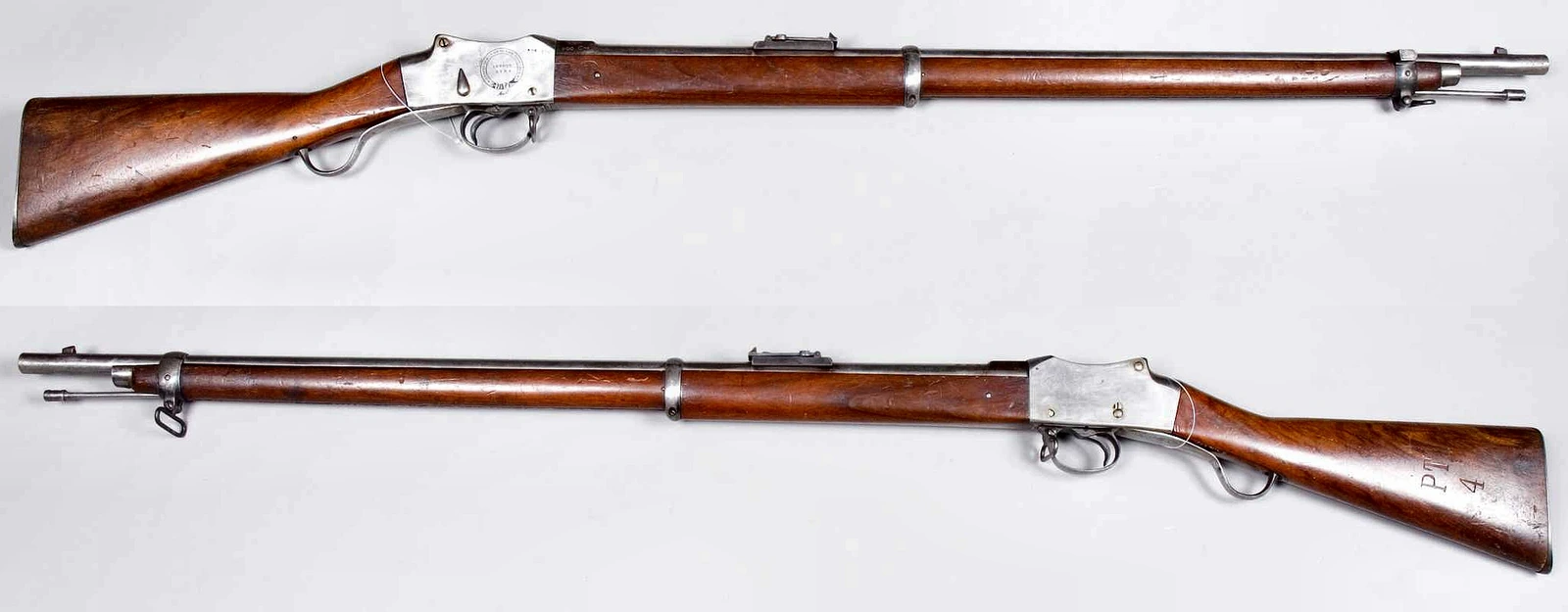 Two views of a Martini-Henry rifle on a pale background, left and right sides, with a full wooden stock, a curved underlever ahead of the trigger guard, a flat steel receiver and a fixed rear sight ahead of the receiver
