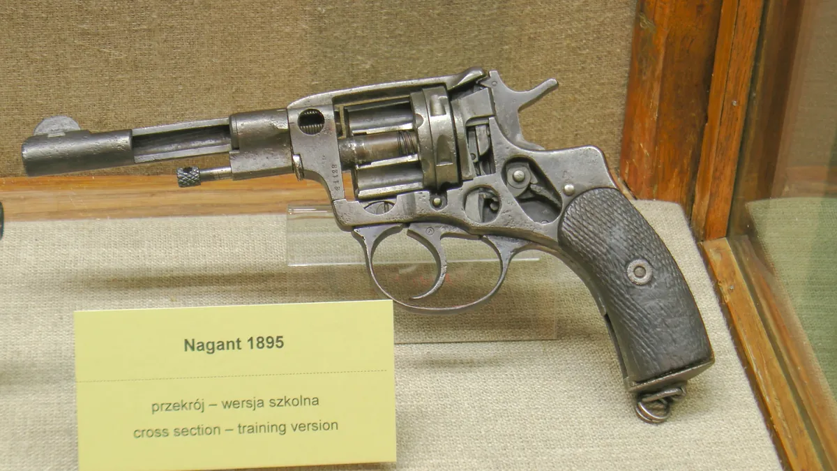 A revolver sectioned lengthwise to reveal its internal cylinder, hammer and trigger mechanism, with two cartridges resting beside it.