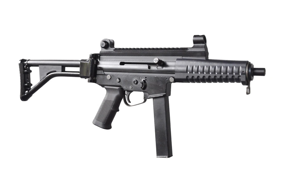 A black compact submachine gun with a rail-equipped upper receiver, a folding stock, a pistol grip and a curved magazine, photographed against a plain white background