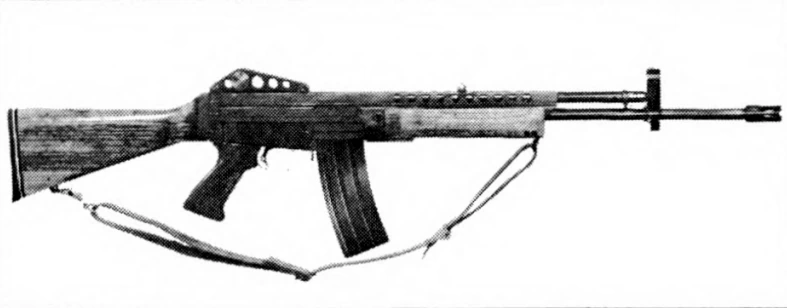 A rifle in profile with a slotted flash suppressor, a straight synthetic handguard and a curved box magazine.