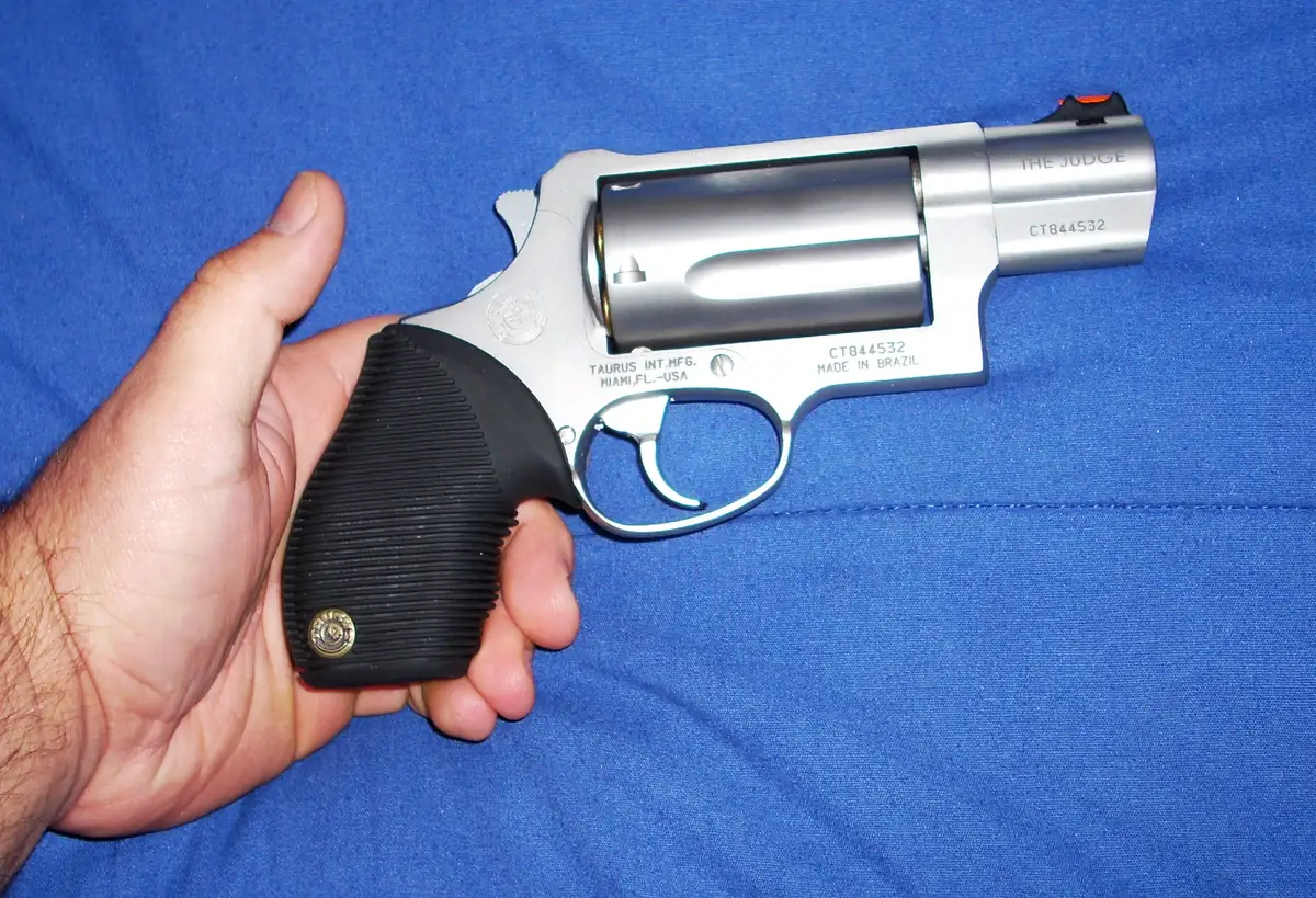 A stainless steel snub-nosed revolver with a spurless hammer held in a hand
