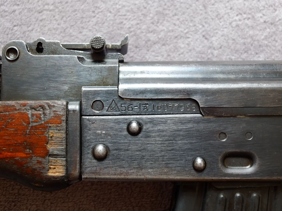 Close-up of a triangle-and-66 factory marking stamped into a rifle receiver
