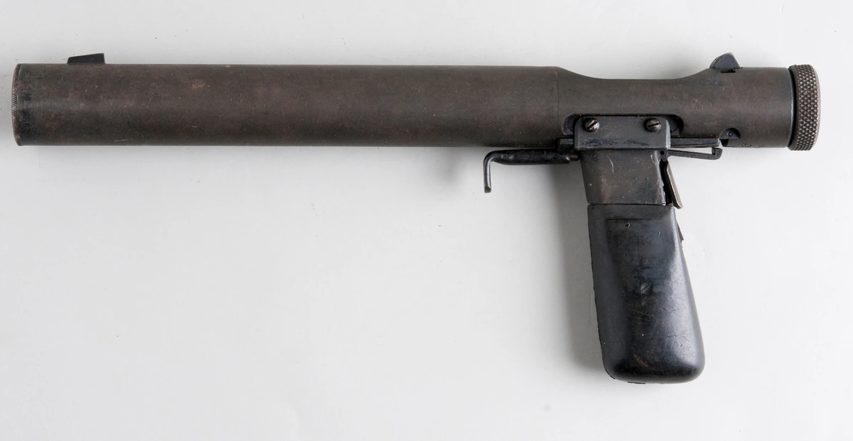 A Welrod Mk IIA pistol, a plain metal tube with magazine grip, laid on a flat surface