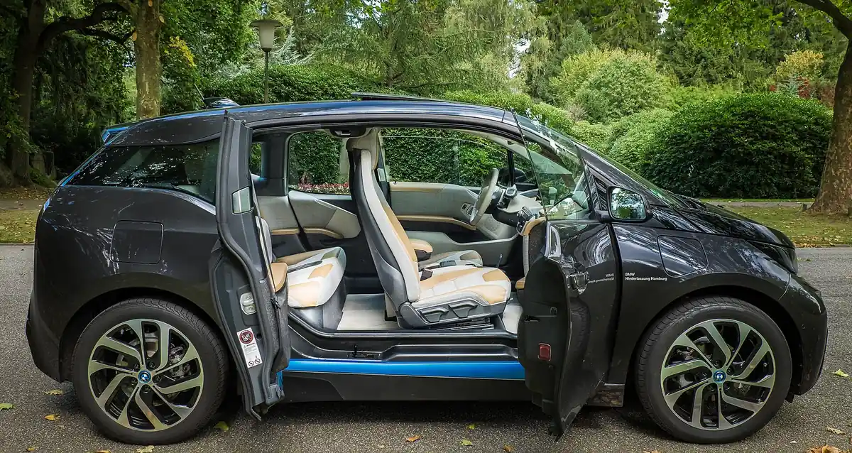 Black BMW i3 with its front-hinged and rear-hinged coach doors both open, showing the pillarless door aperture and cream interior