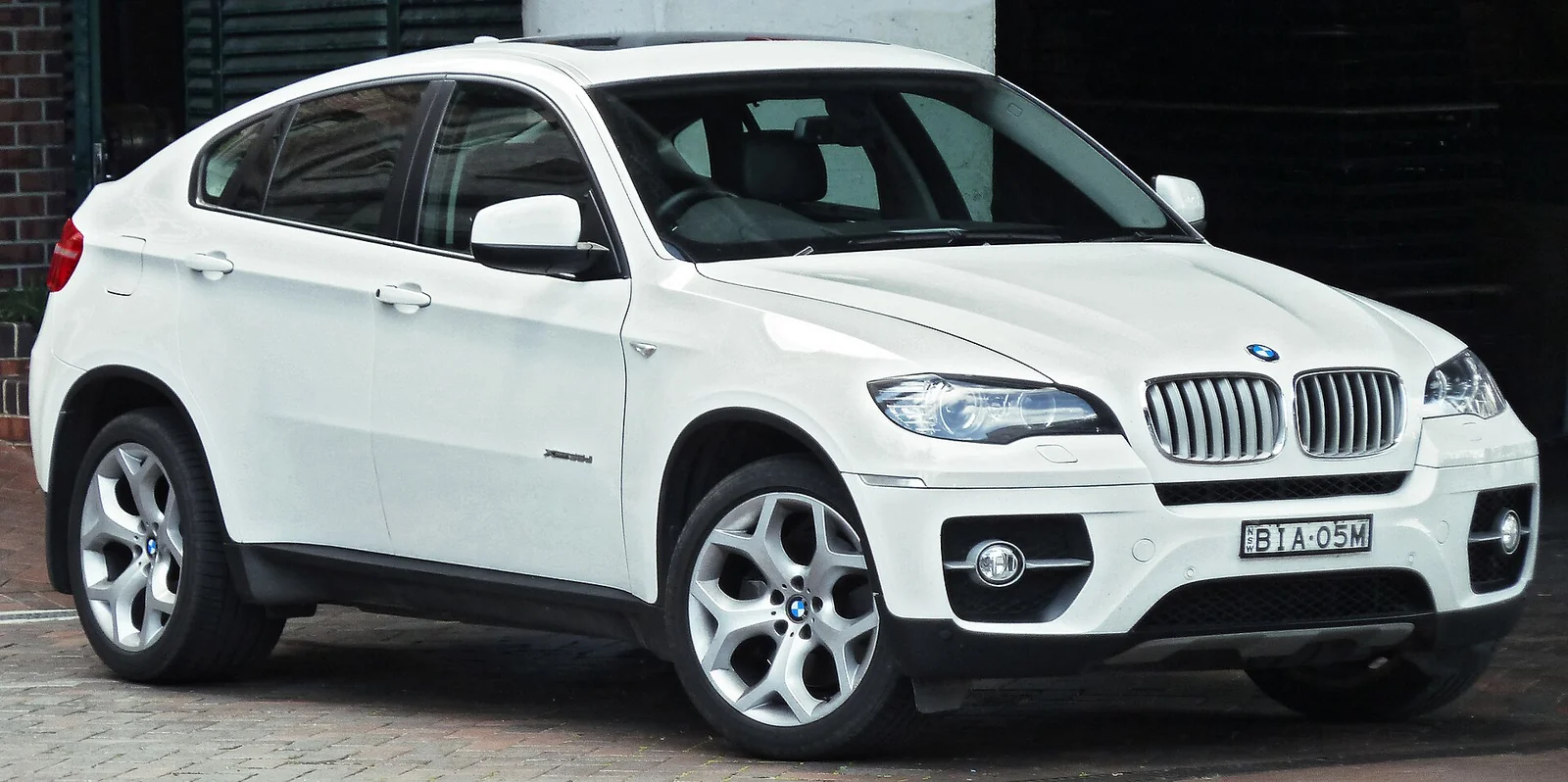 White first-generation BMW X6 photographed from the front three-quarter angle, showing its sloping coupe-like roofline over an SUV body