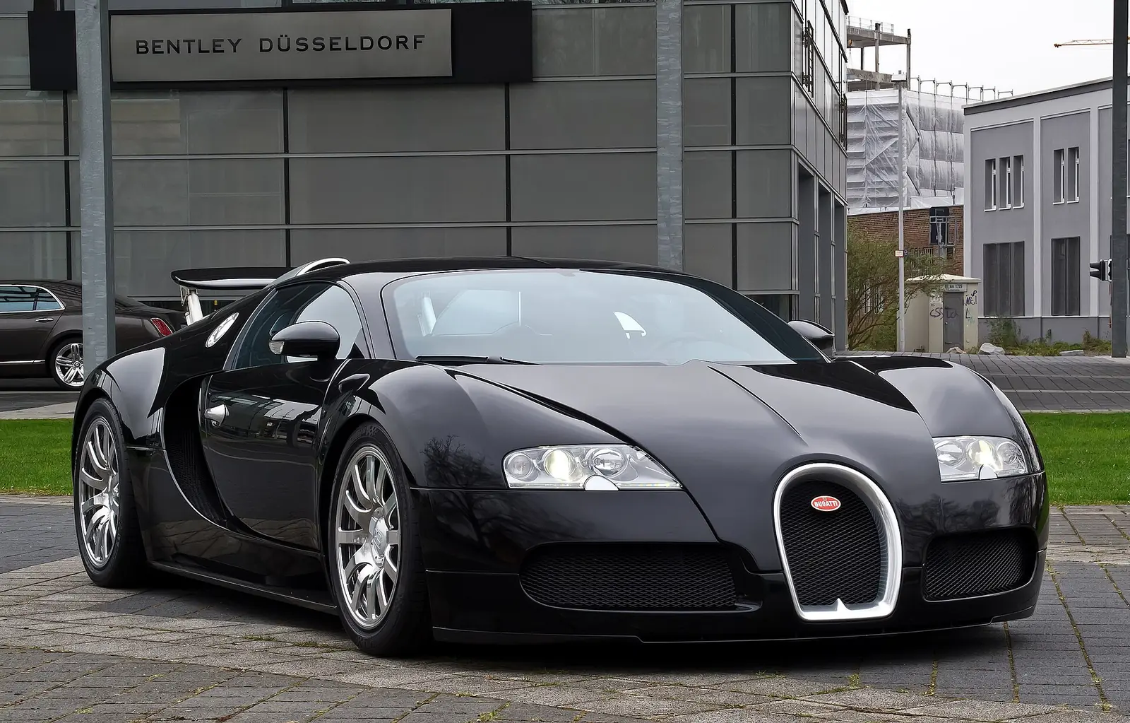 Black Bugatti Veyron 16.4 photographed from the front three-quarter angle, showing its horseshoe-shaped chrome grille and twin roof-mounted air intakes