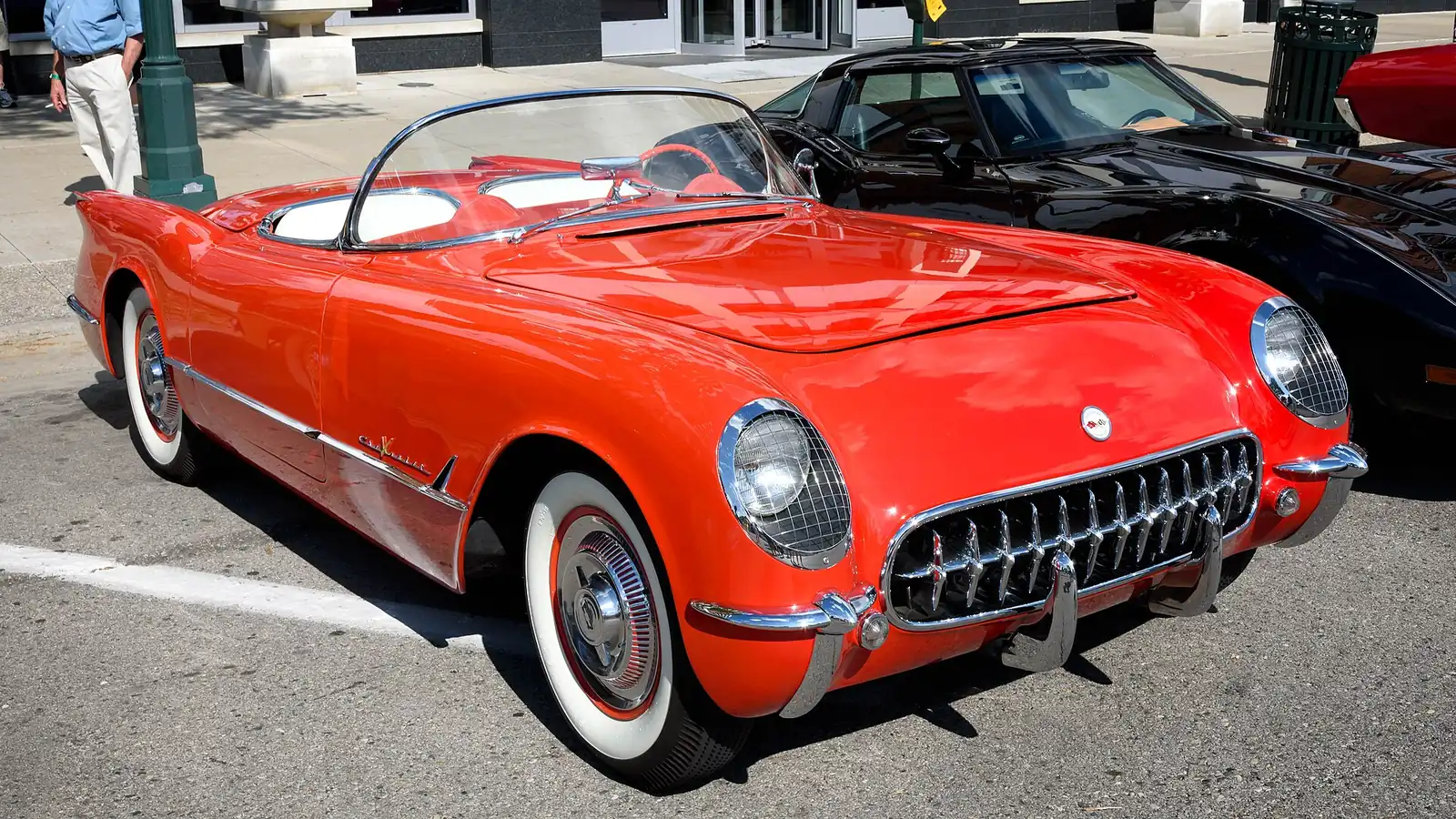 Red 1955 Chevrolet Corvette convertible photographed from the front three-quarter angle, showing its chrome grille and wraparound windscreen