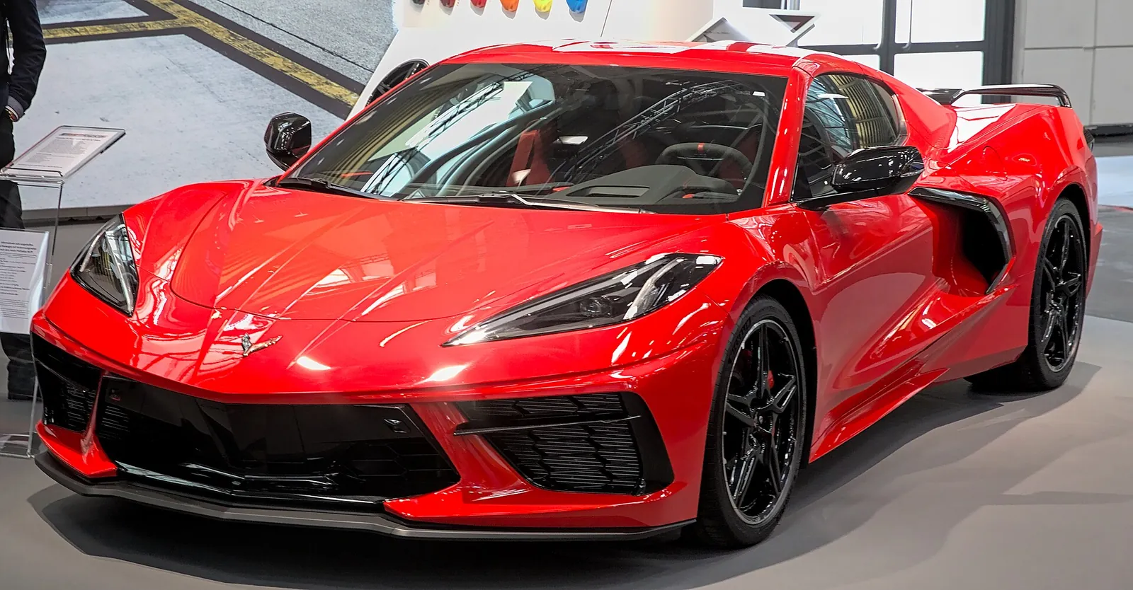 Red mid-engined Chevrolet Corvette C8 photographed from the front three-quarter angle at a motor show