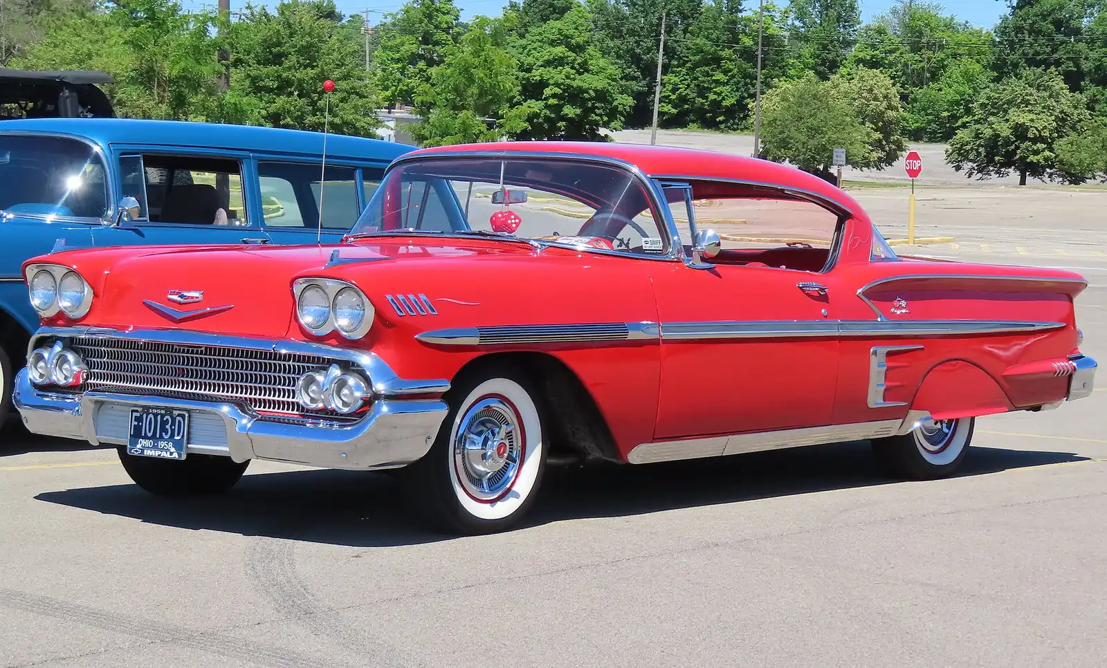 Red and white 1958 Chevrolet Bel Air Impala Sport Coupe photographed from the front three-quarter angle, showing its chrome grille and tailfins