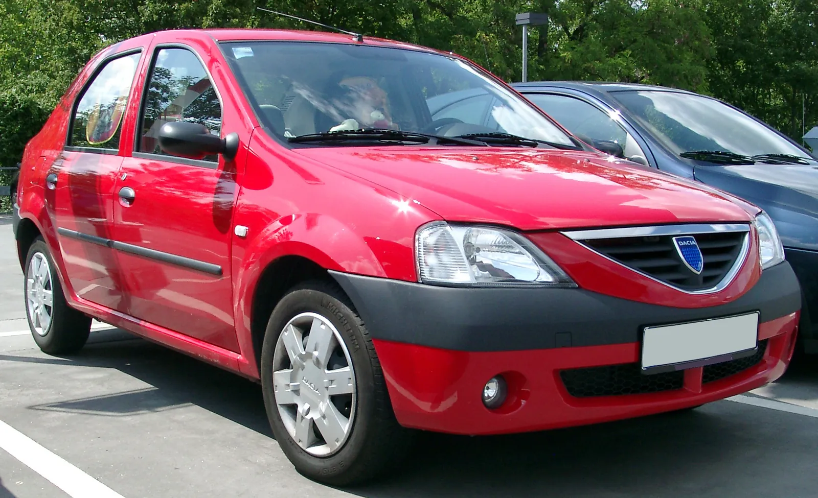 Red first-generation Dacia Logan saloon photographed from the front three-quarter angle