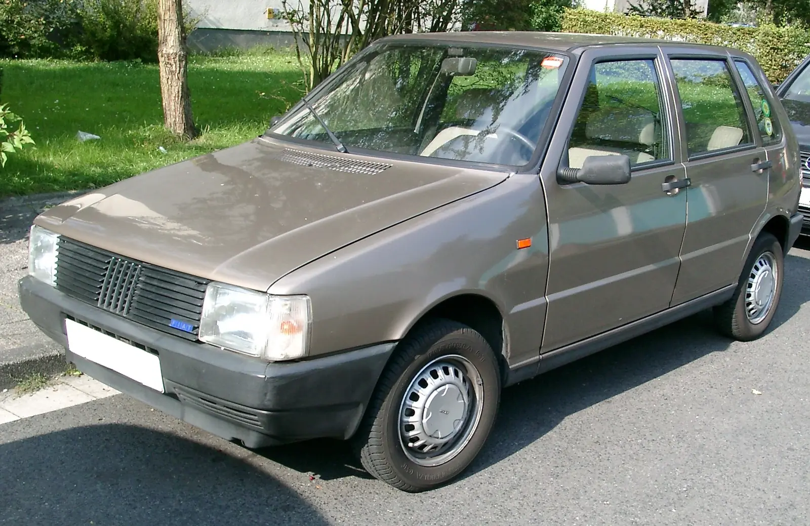 Beige Fiat Uno photographed from the front three-quarter angle, showing its tall, square Giugiaro-designed hatchback body
