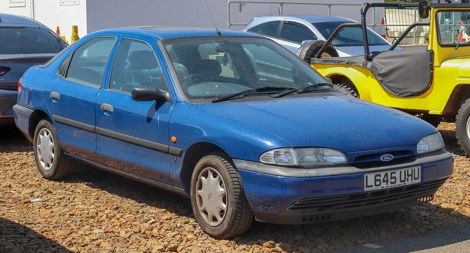 Blue first-generation Ford Mondeo saloon photographed from the front three-quarter angle in a gravel car park