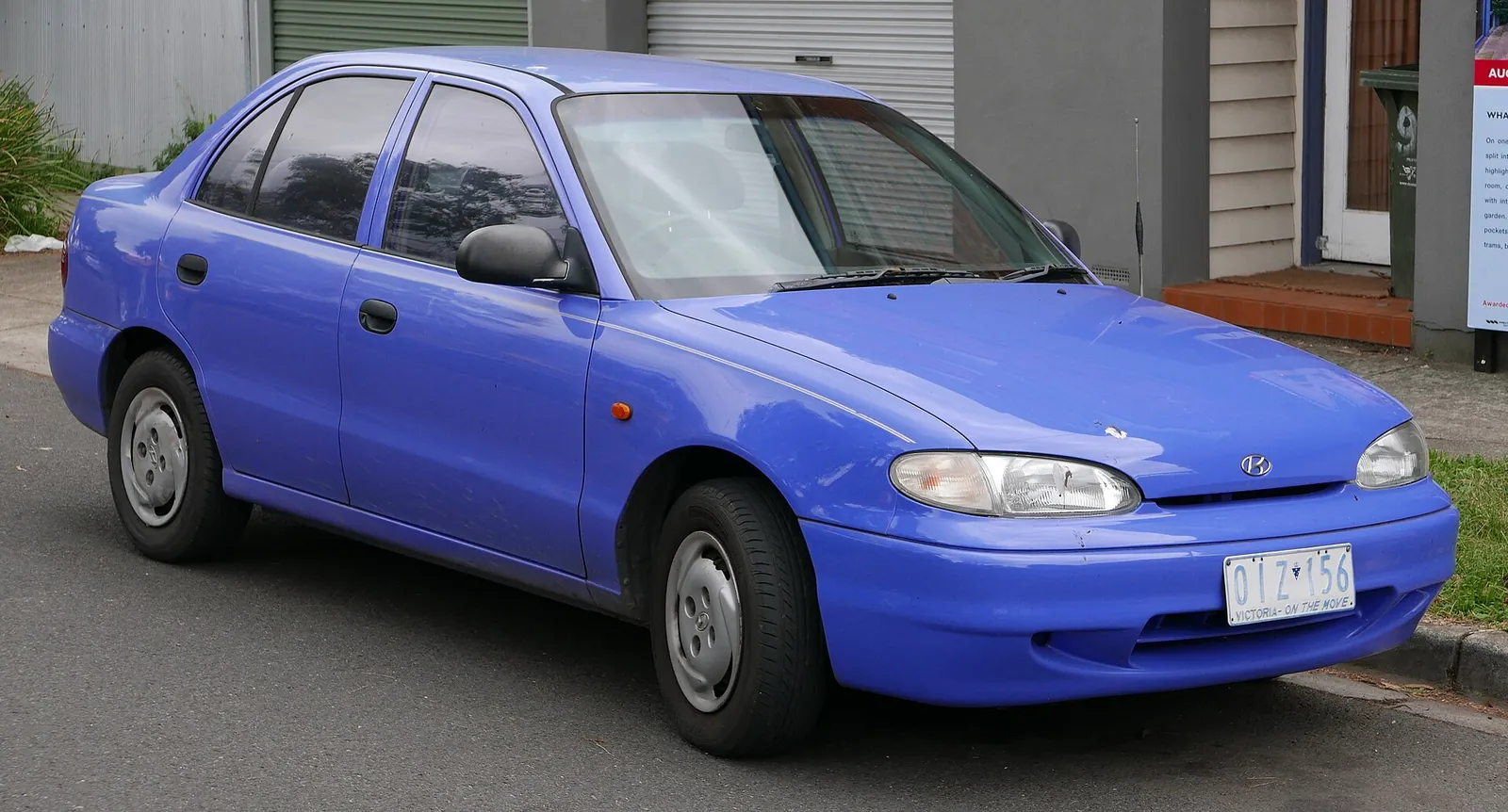 Blue Hyundai Excel/Accent X3 four-door sedan photographed from the front three-quarter angle, parked on a residential street