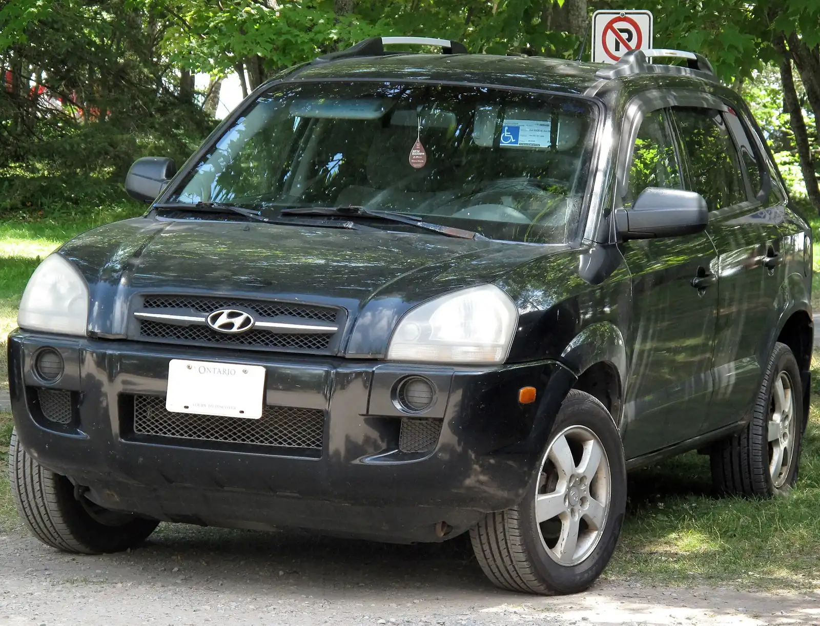 Black first-generation Hyundai Tucson photographed from the front three-quarter angle with a roof rack fitted