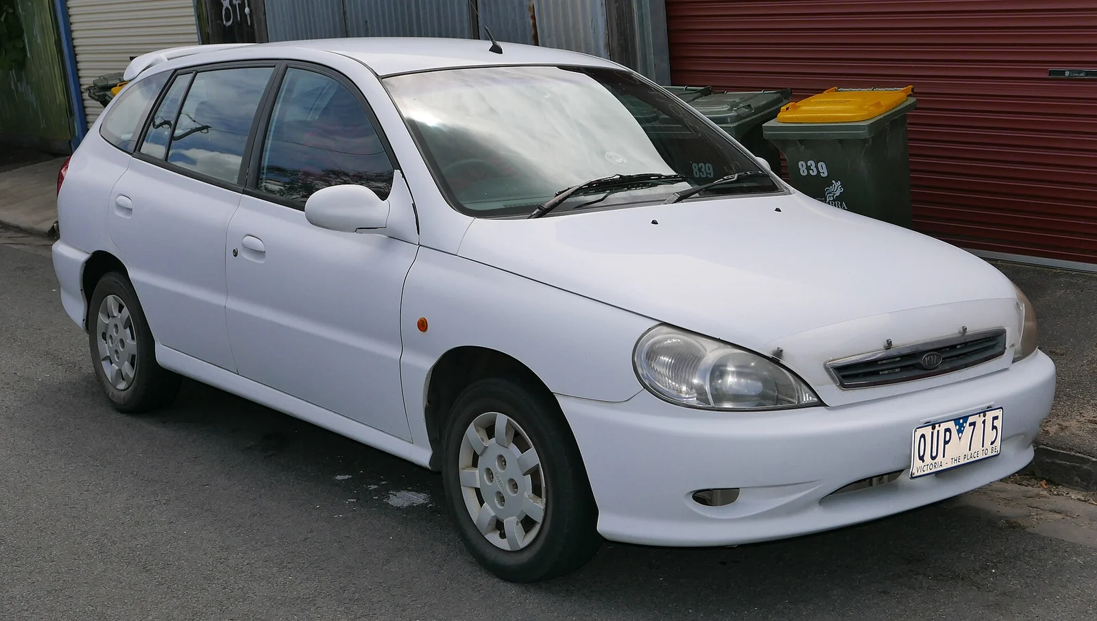 White first-generation Kia Rio hatchback photographed from the front three-quarter angle