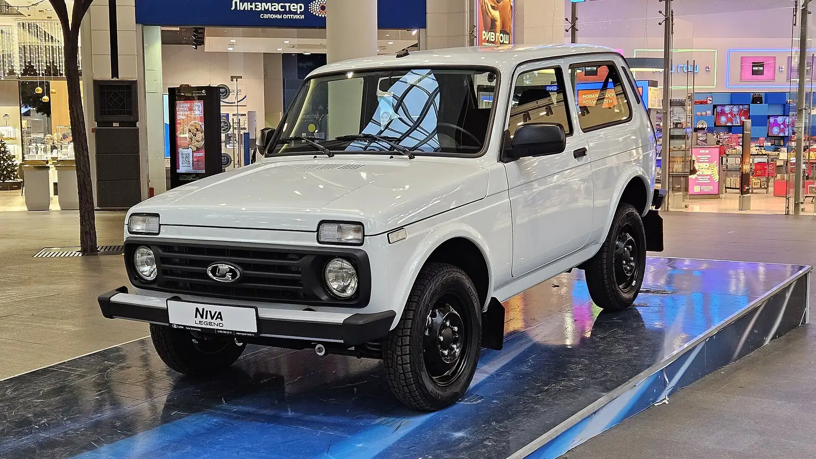 White current-generation Lada Niva Legend photographed from the front three-quarter angle indoors, with a Niva badge visible on the grille