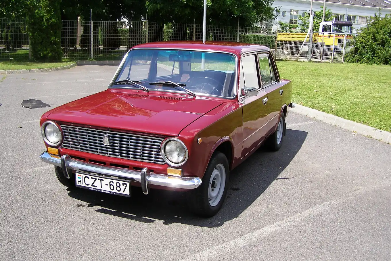 Red Lada VAZ-2101 saloon photographed from the front three-quarter angle, showing its rounded Fiat-derived nose and chrome bumpers