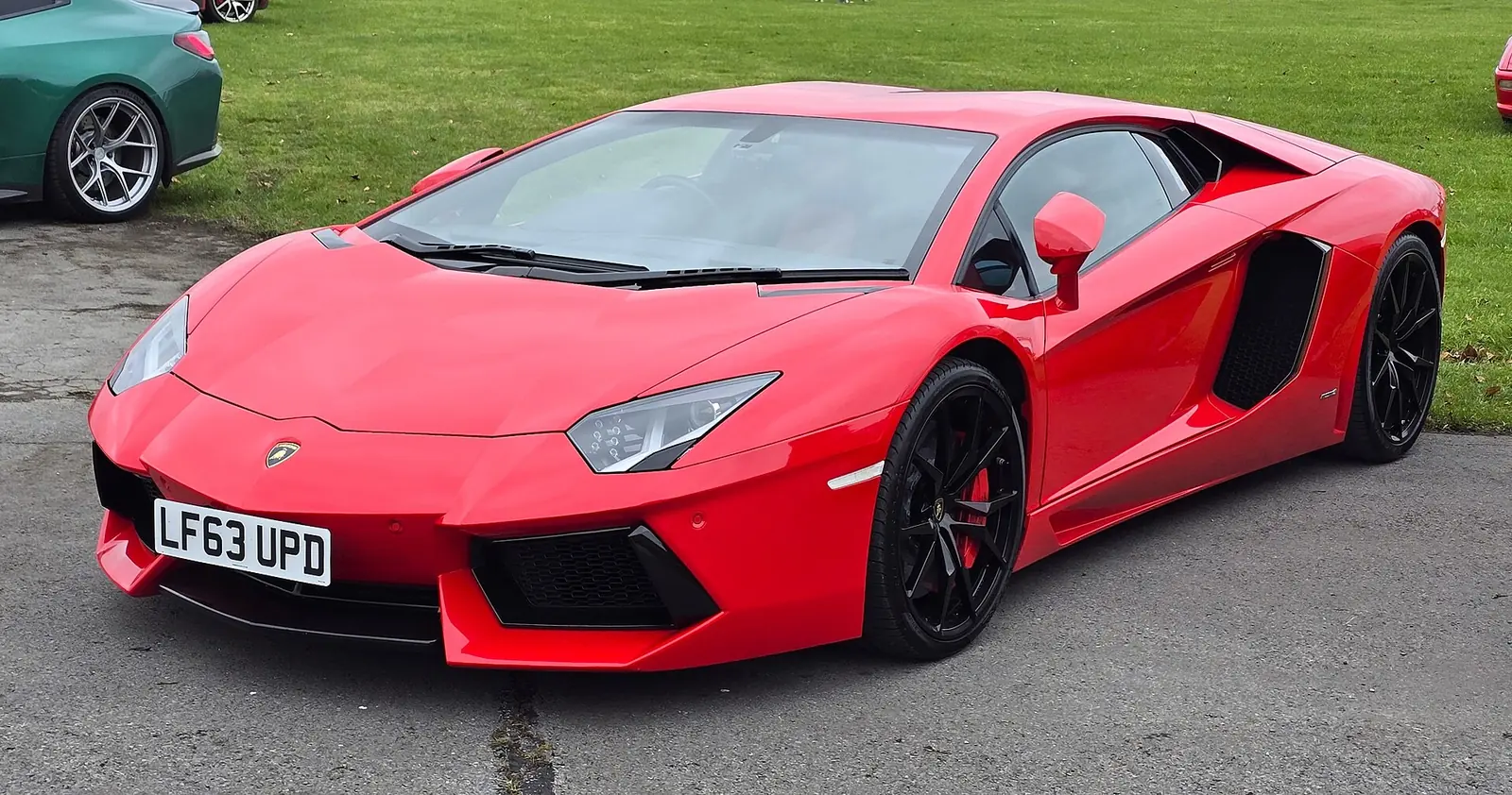 Red Lamborghini Aventador LP 700-4 photographed from the front three-quarter angle, showing its angular wedge nose and scissor door