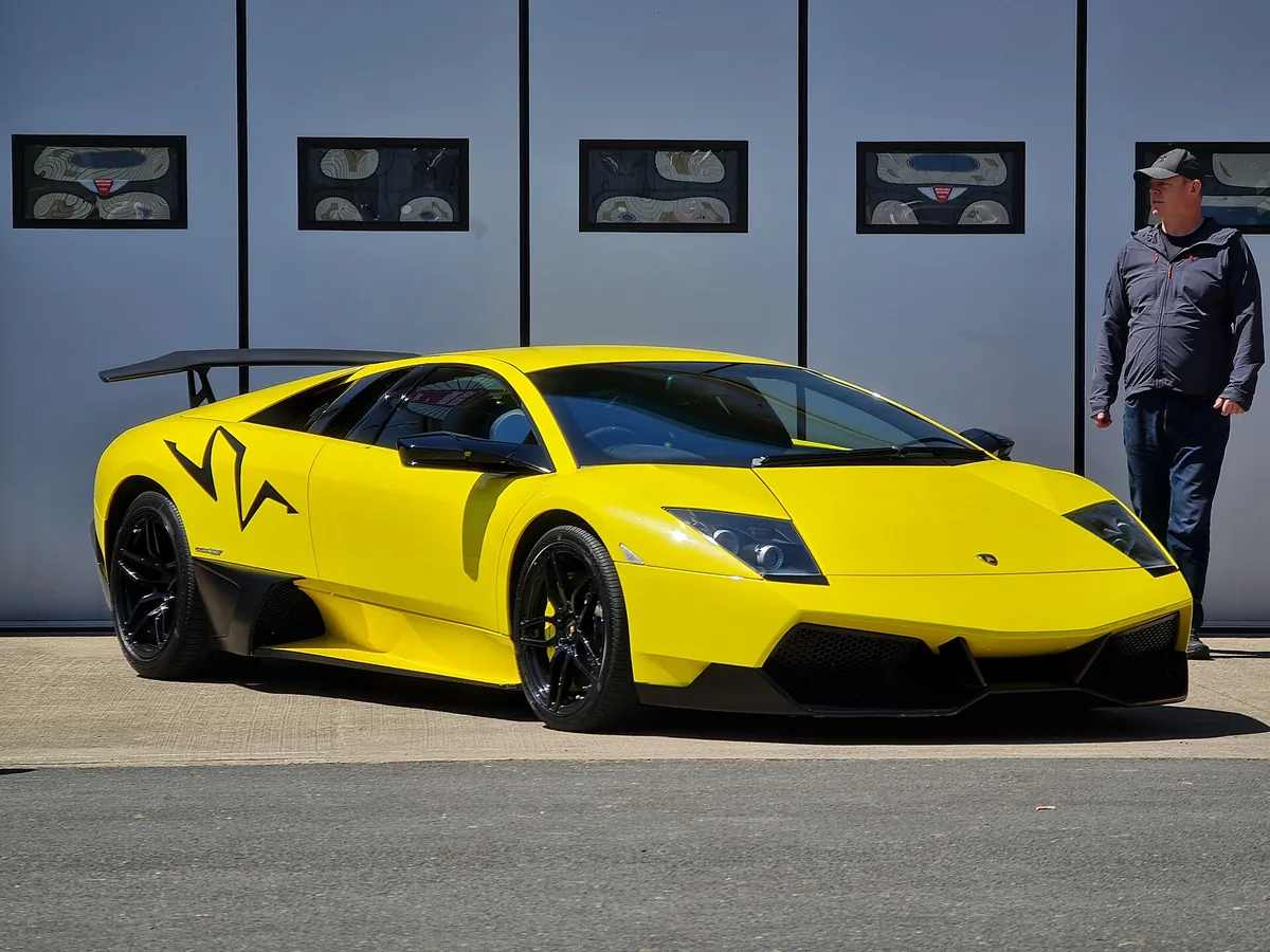 Yellow Lamborghini Murciélago LP670-4 SuperVeloce parked outdoors, showing the enlarged front air intakes and lower front spoiler