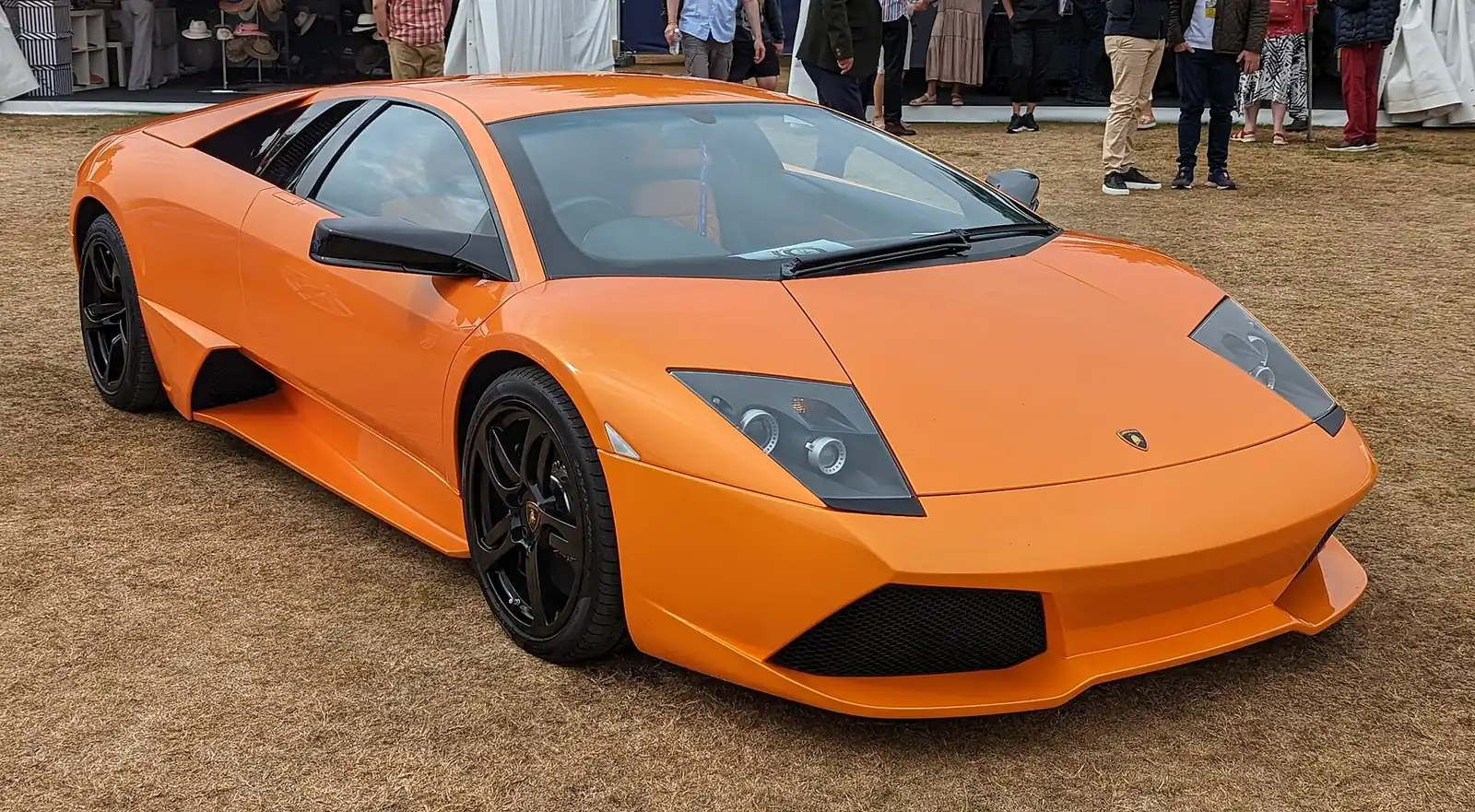 Orange Lamborghini Murciélago photographed from the front three-quarter angle, showing the scissor door and angular headlamps