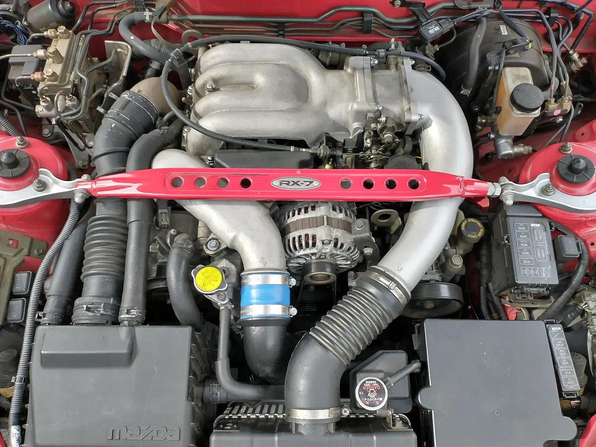 Mazda 13B-REW rotary engine installed in an FD3S RX-7 engine bay, showing its sequential twin-turbocharger plumbing