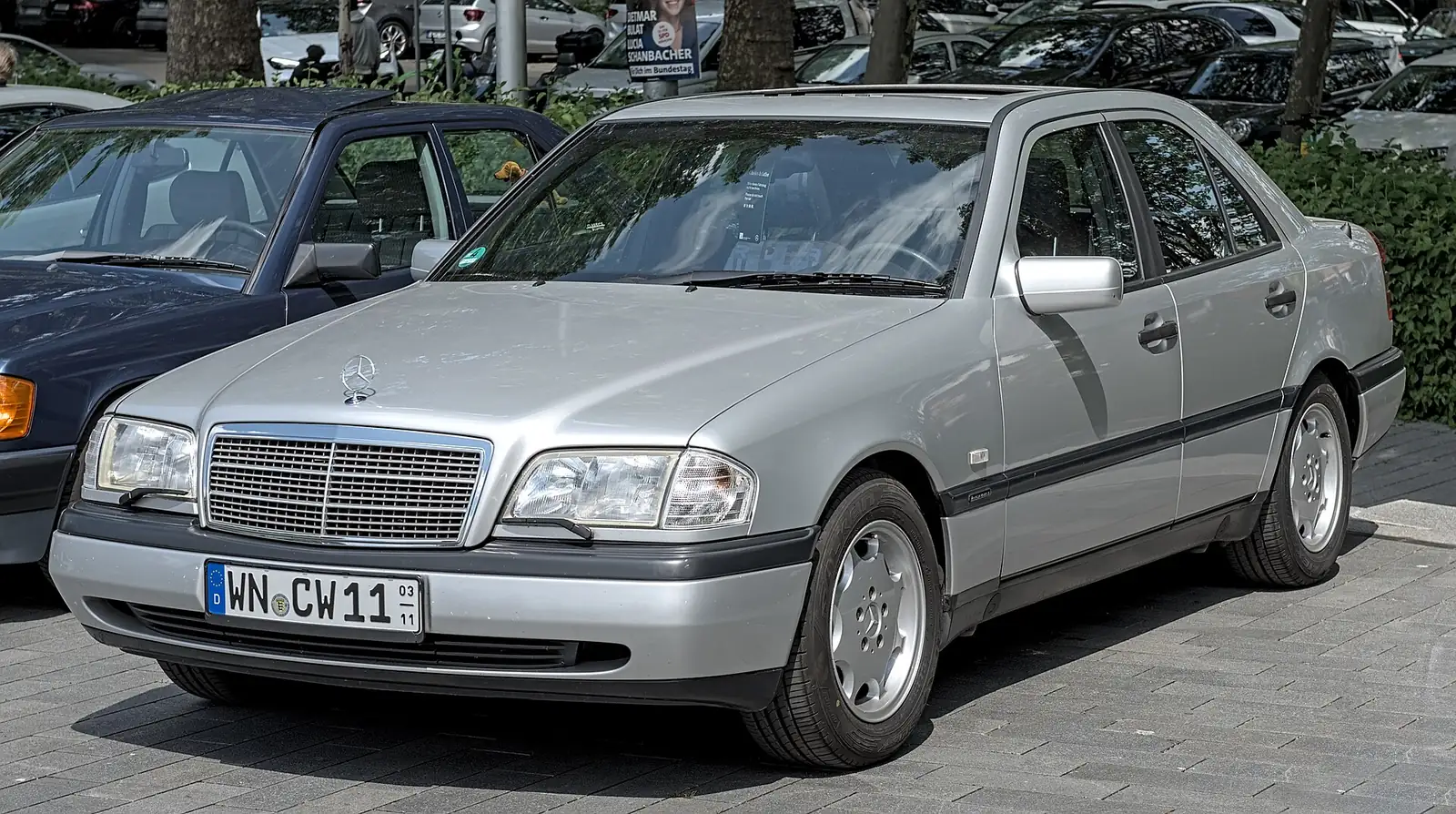 Silver first-generation Mercedes-Benz C-Class sedan photographed from the front three-quarter angle in a car park