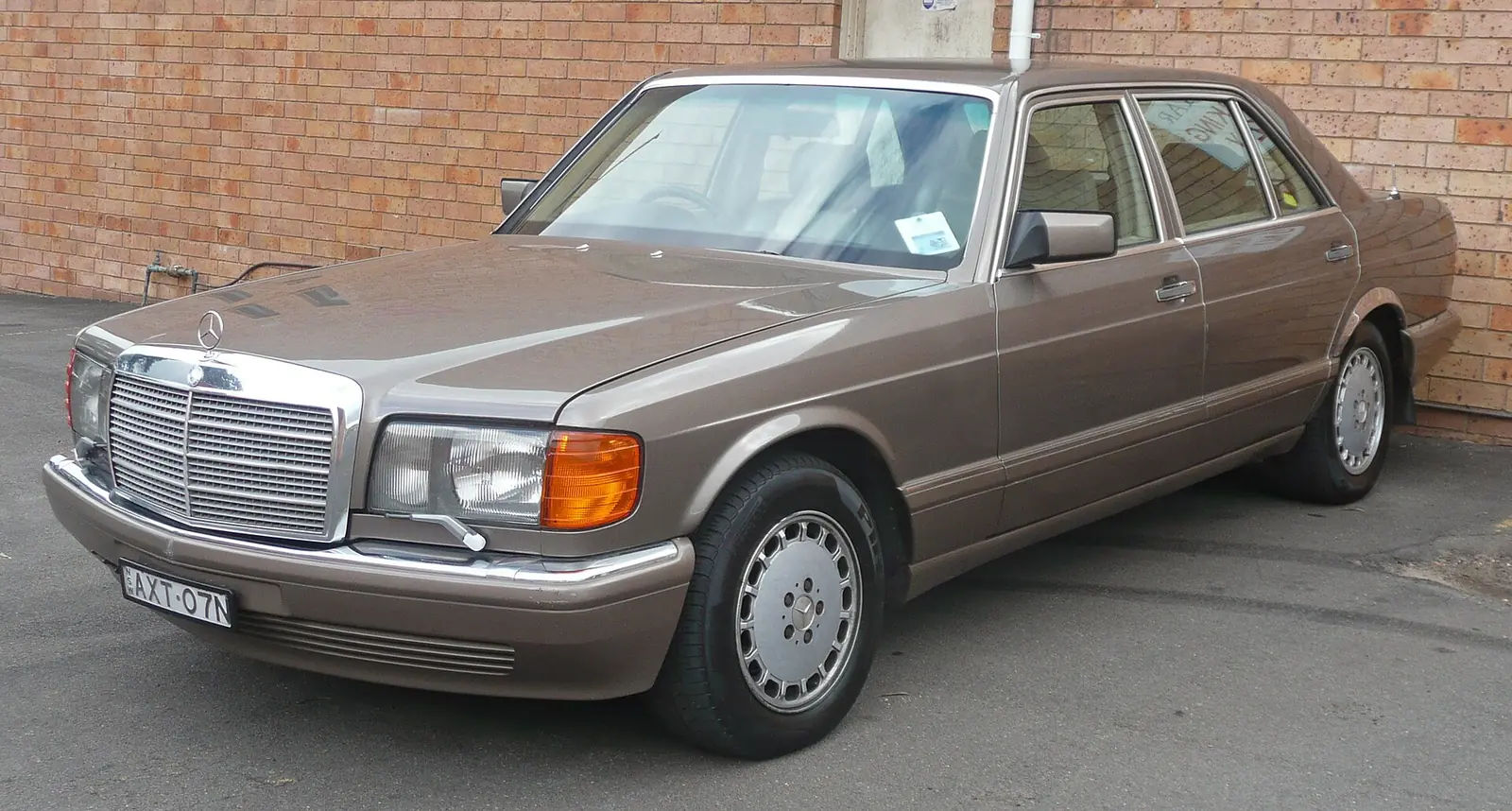 Dark blue facelifted Mercedes-Benz W126 S-Class saloon on display indoors, photographed from the front three-quarter angle