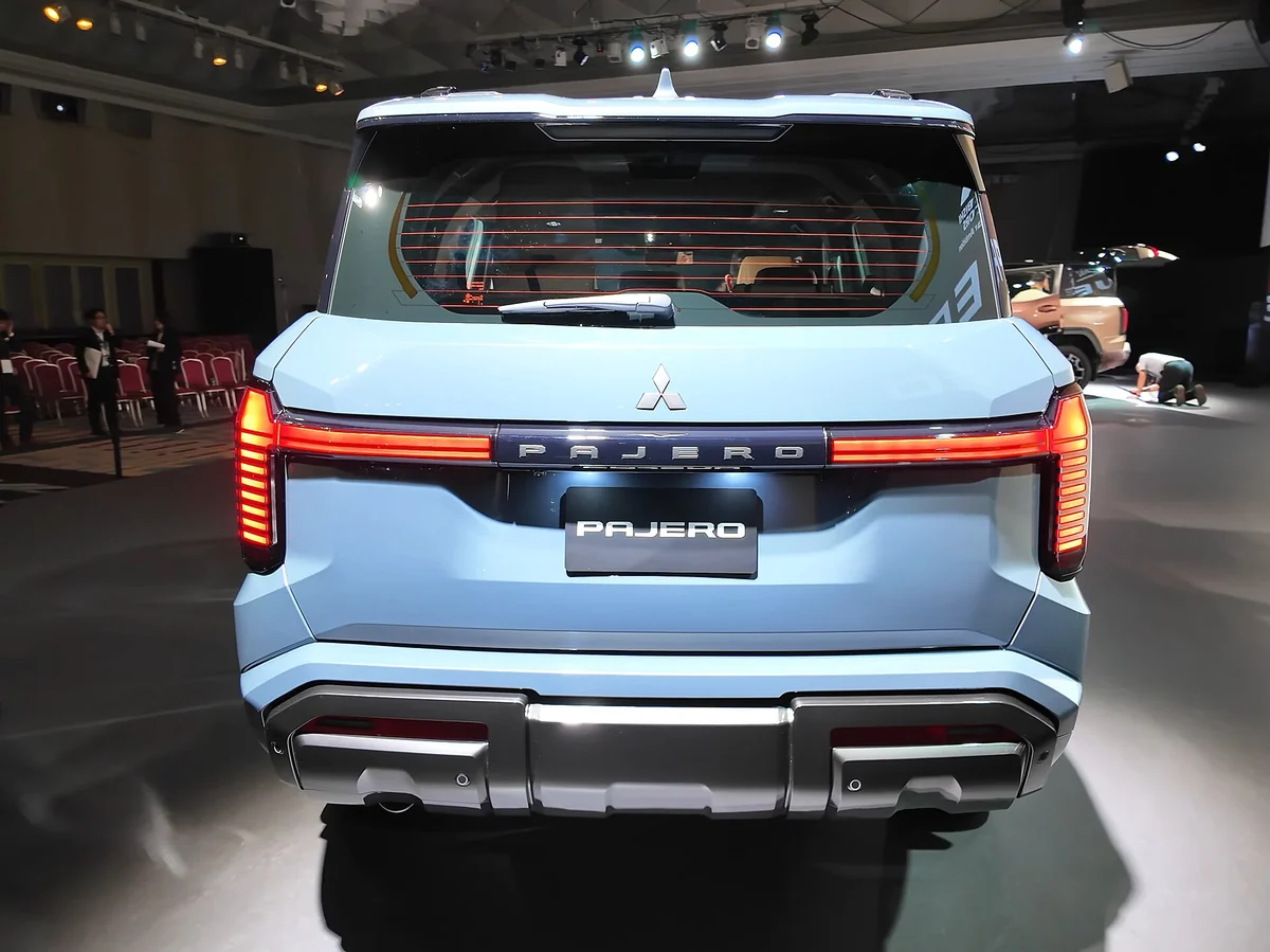 Rear view of a light blue fifth-generation Mitsubishi Pajero at its launch event, showing its full-width T-shaped tail lamp and Pajero badging