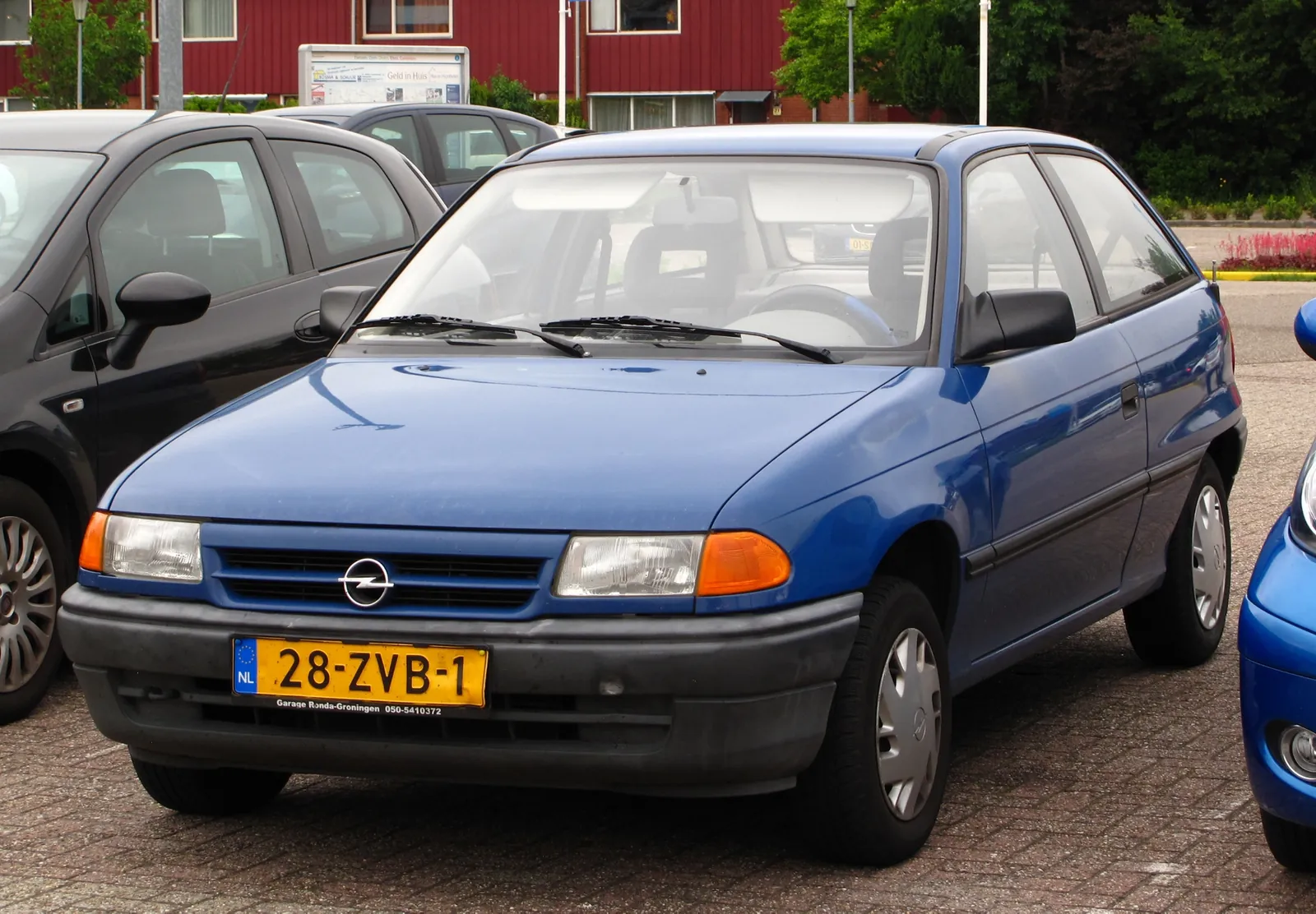 Blue first-generation Opel Astra hatchback parked kerbside, photographed from the front three-quarter angle