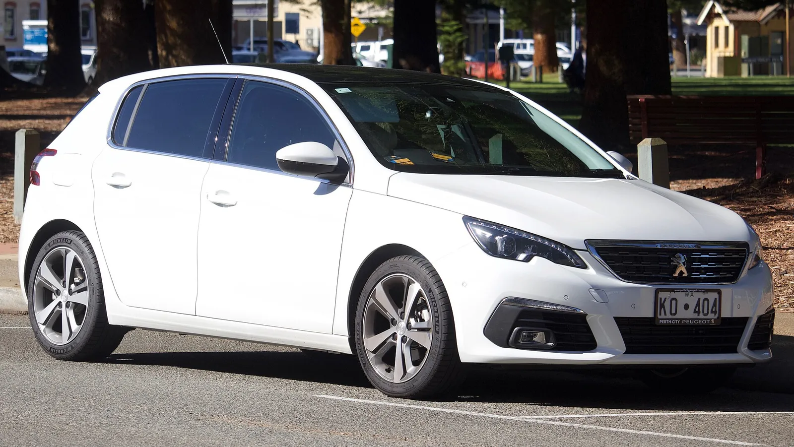 White facelifted second-generation Peugeot 308 hatchback photographed from the front three-quarter angle in a car park