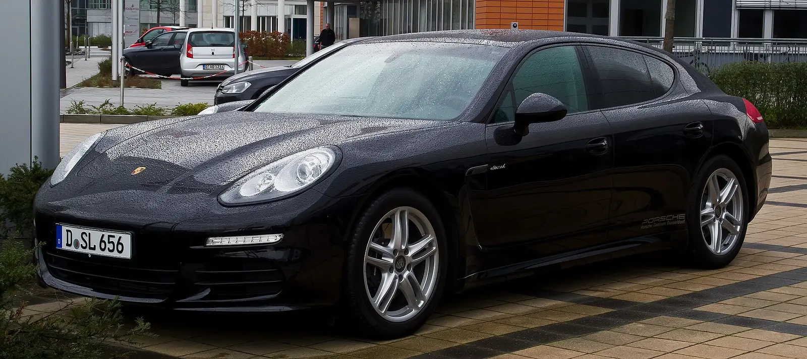 Black facelifted Porsche Panamera Diesel liftback photographed from the front three-quarter angle outside an office building in the rain